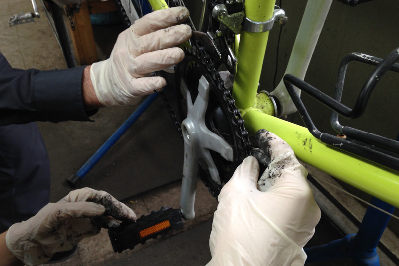 mains gantées qui replace une chaîne de vélo